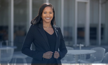 Photo of attractive Black woman standing outdoors in front of an office building.