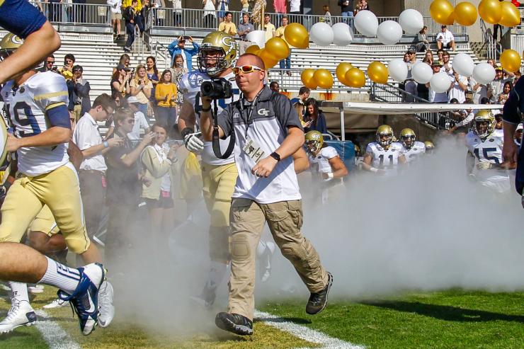 Danny Karnik runs out of the tunnel with the football team to capture a photo during the game against UGA in 2015