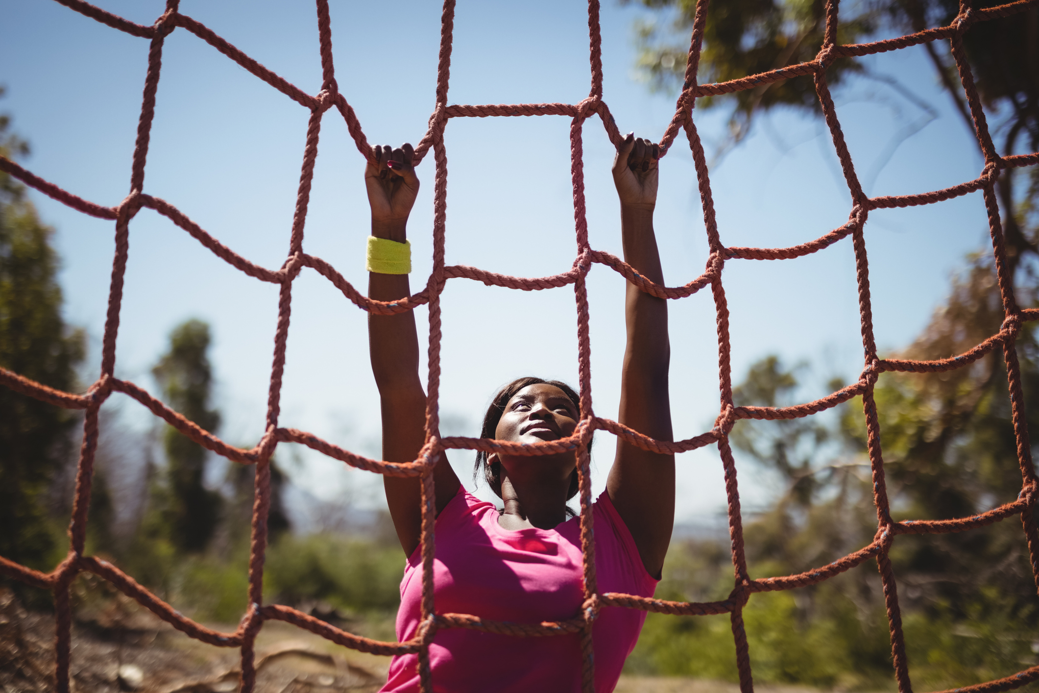 Determined woman climbing a net during obstacle course. Credit iStock.comWavebreakmedia