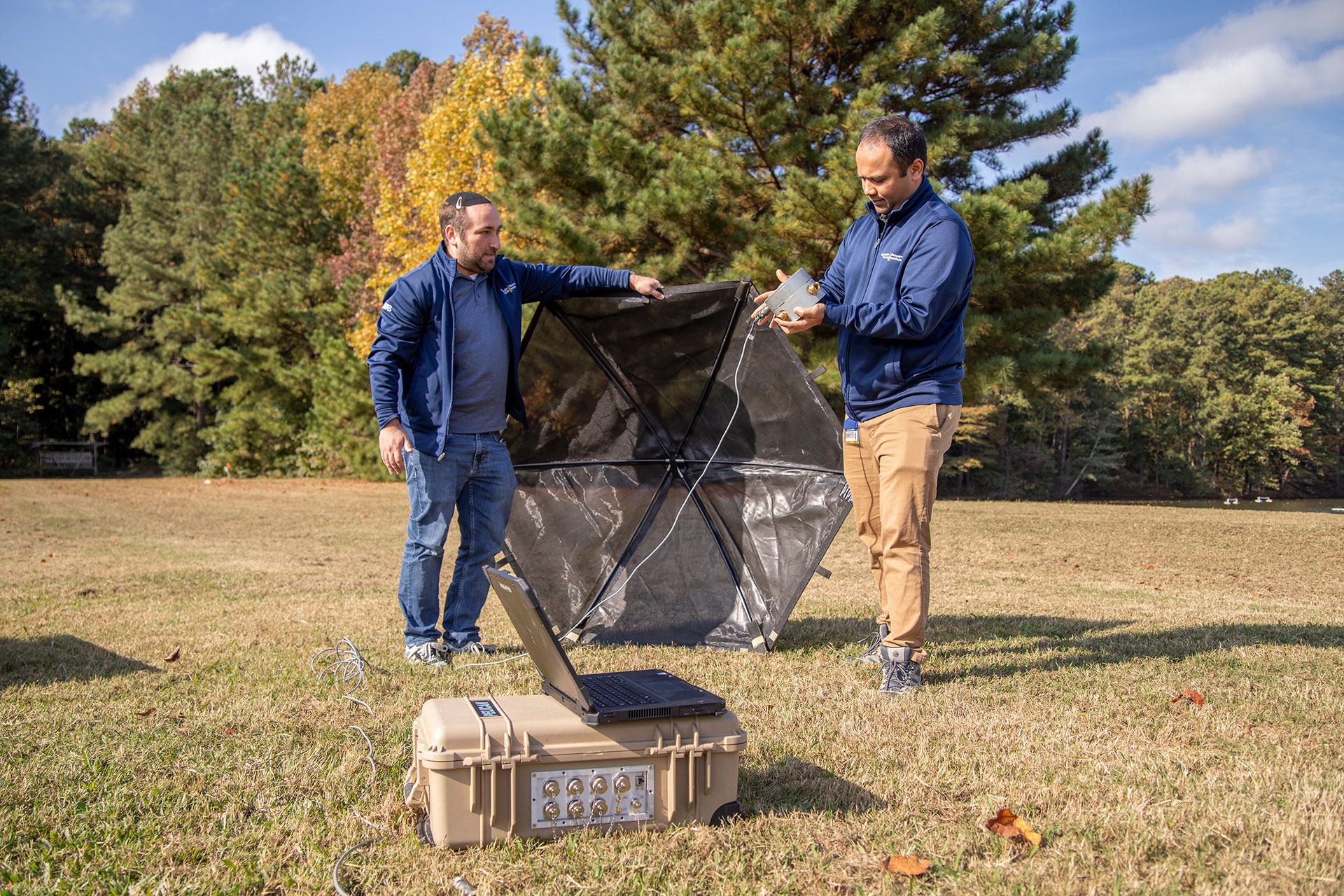Two researchers outdoors assembling an umbrella like device.