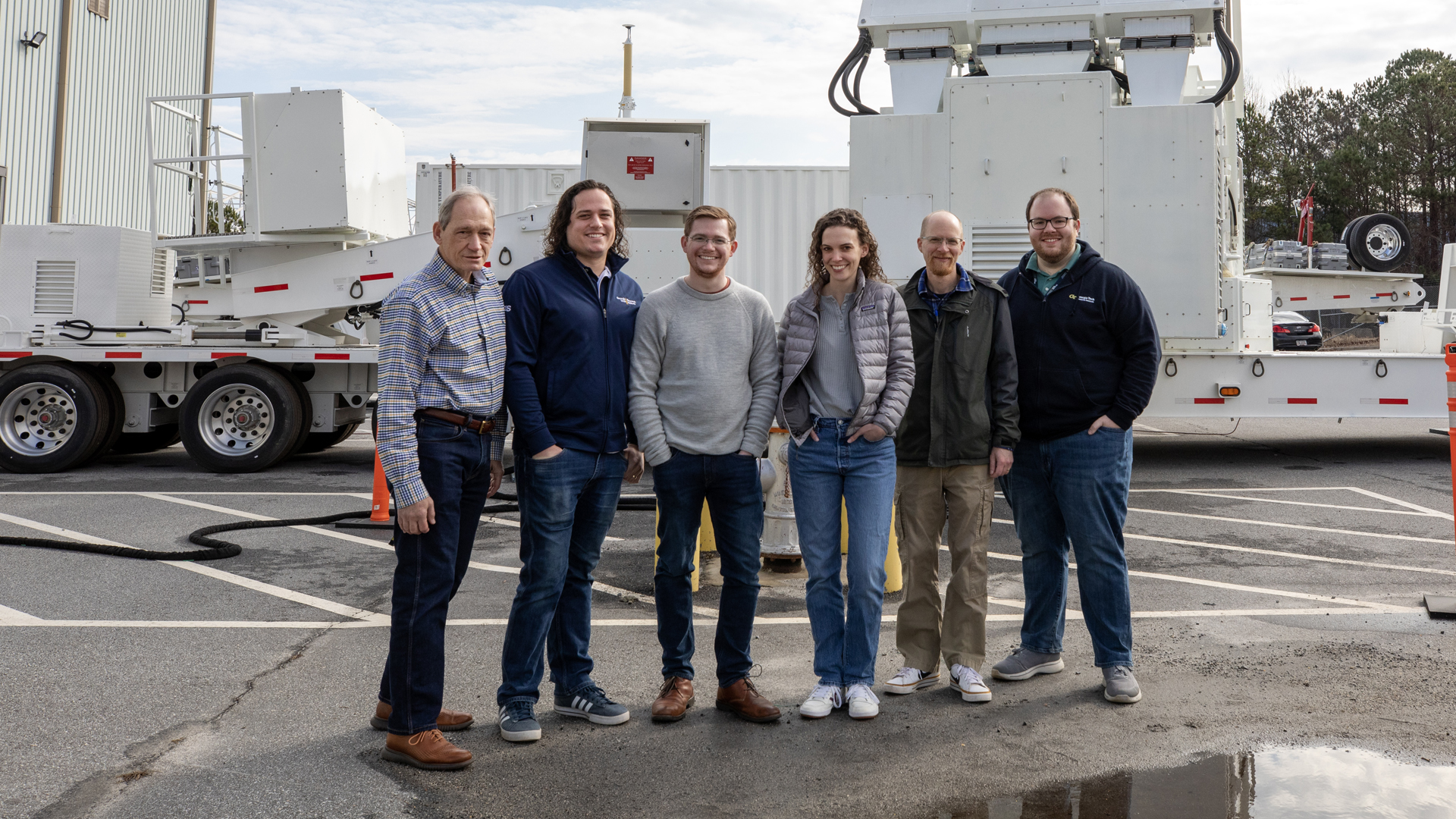 Five male researchers and one female researcher stand in front of the ARTS-V1 system.