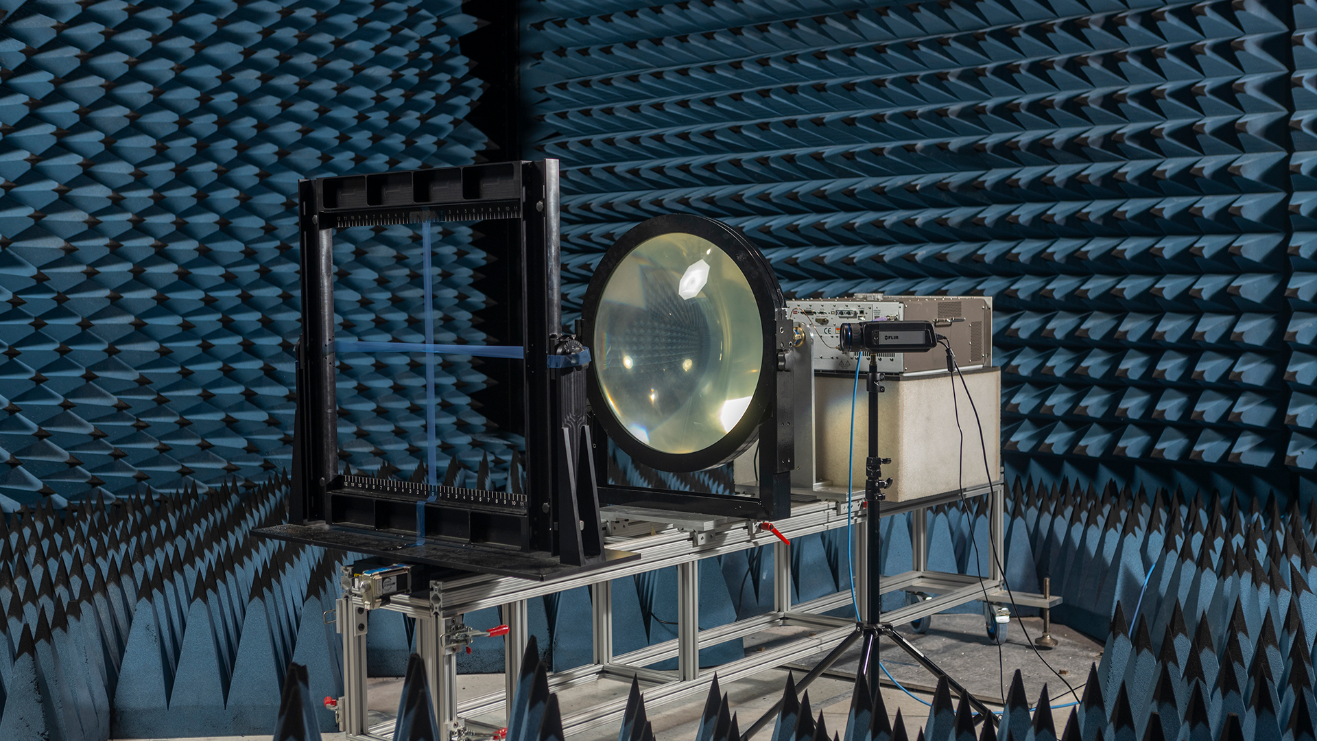 Experimental setup with a very large lens in a dark blue anechoic chamber.