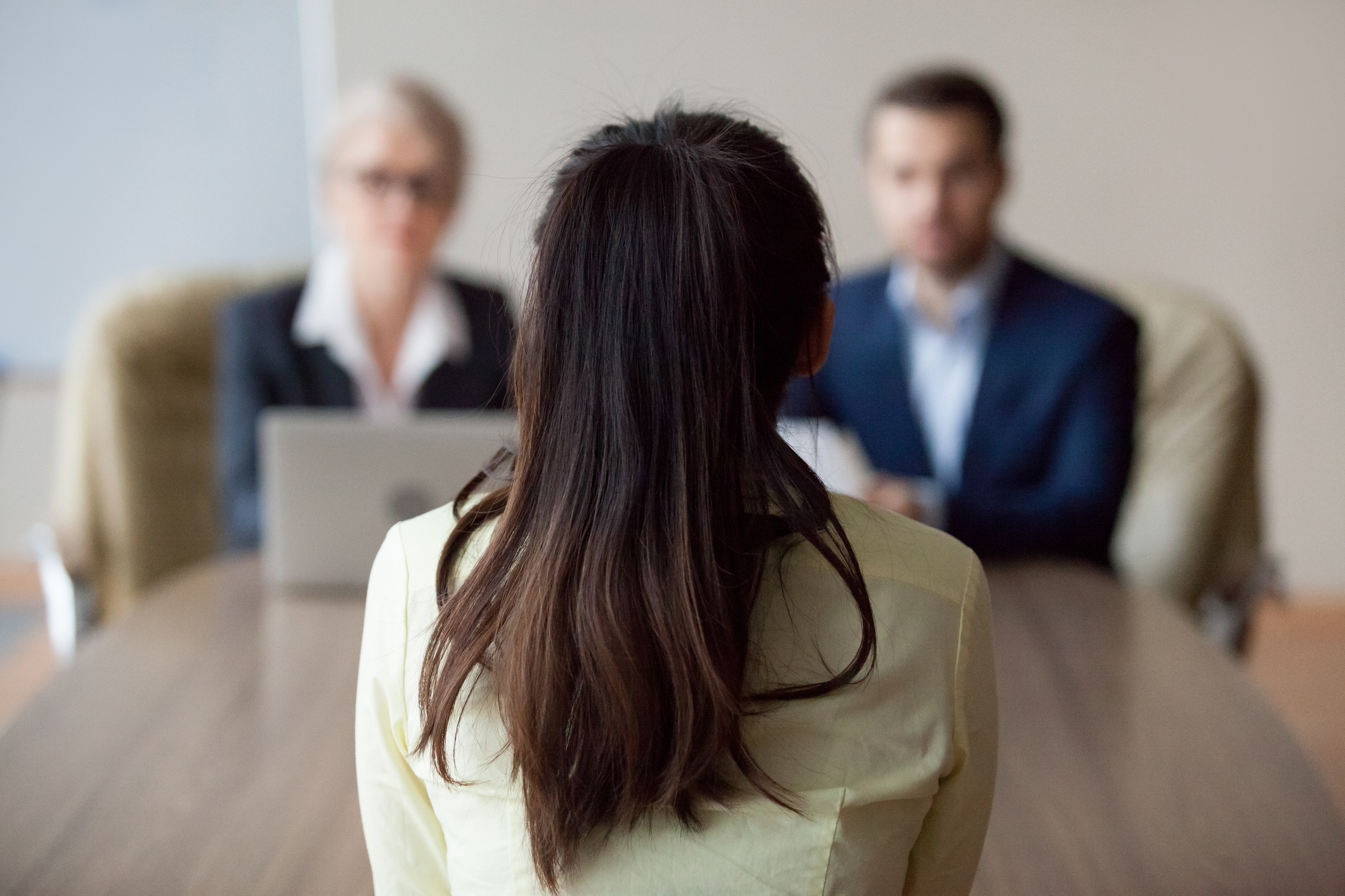 Back of woman's head at a table across two men in an interview