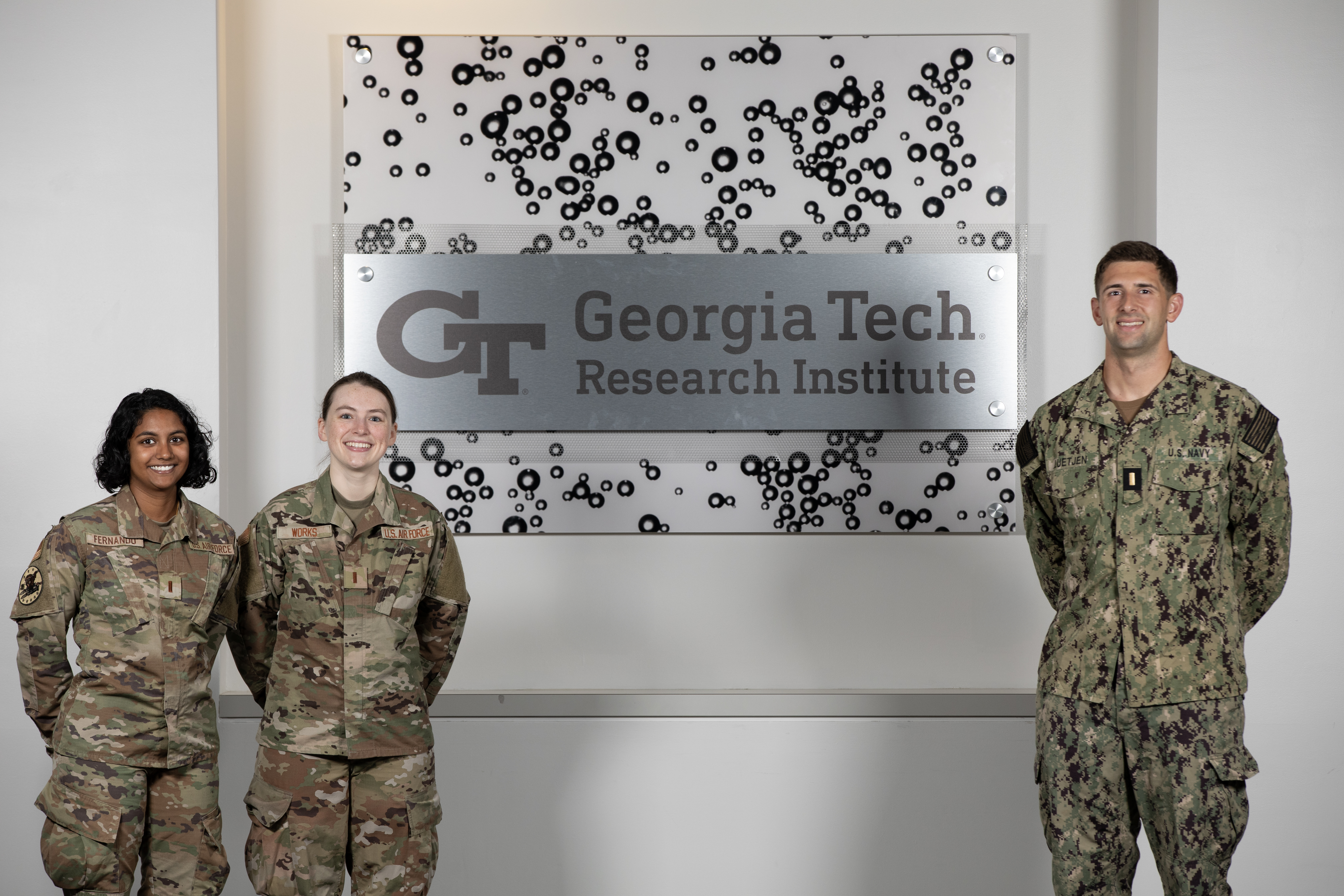 Three members of GTRI's latest Military Graduate Research Program (MGRP) pose in front of GTRI signage.