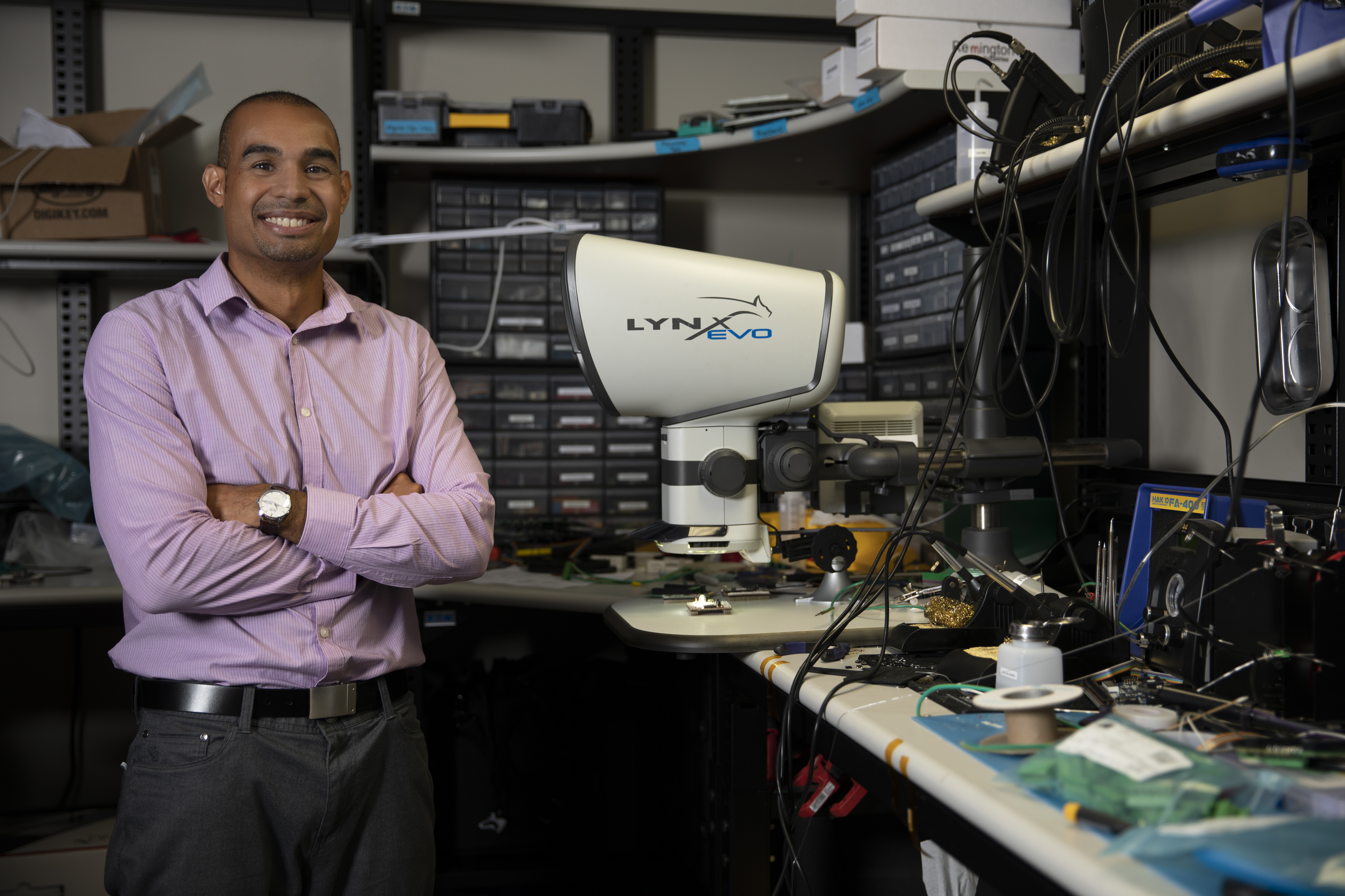 Mike Ruiz, a GTRI principal research engineer, stands in at a work space with an eyepiece-less microscope. (Photo credit: Sean McNeil)