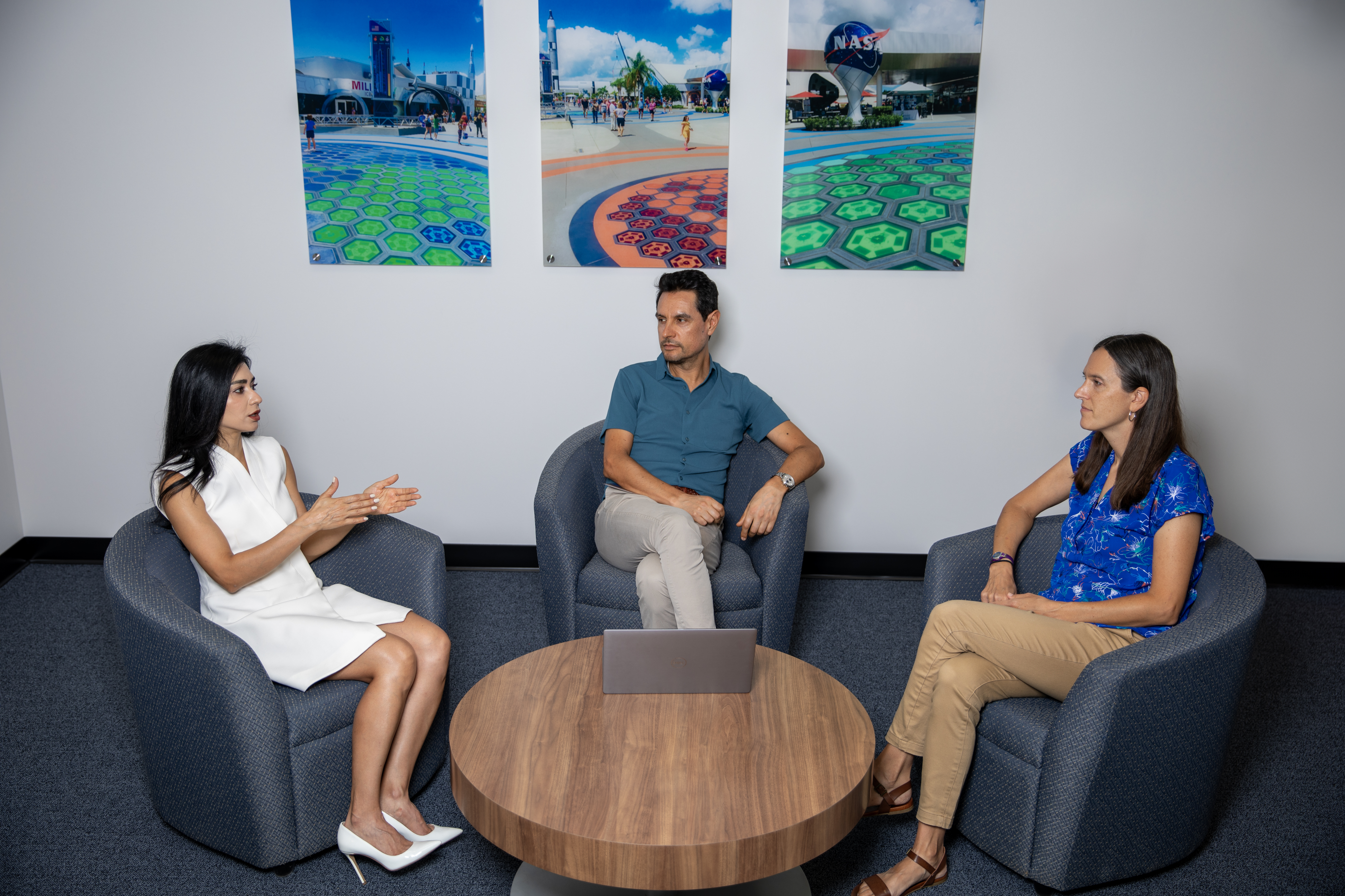 The three GTRI researchers who are supporting this project pictured conversing in chairs surrounding a circular table.