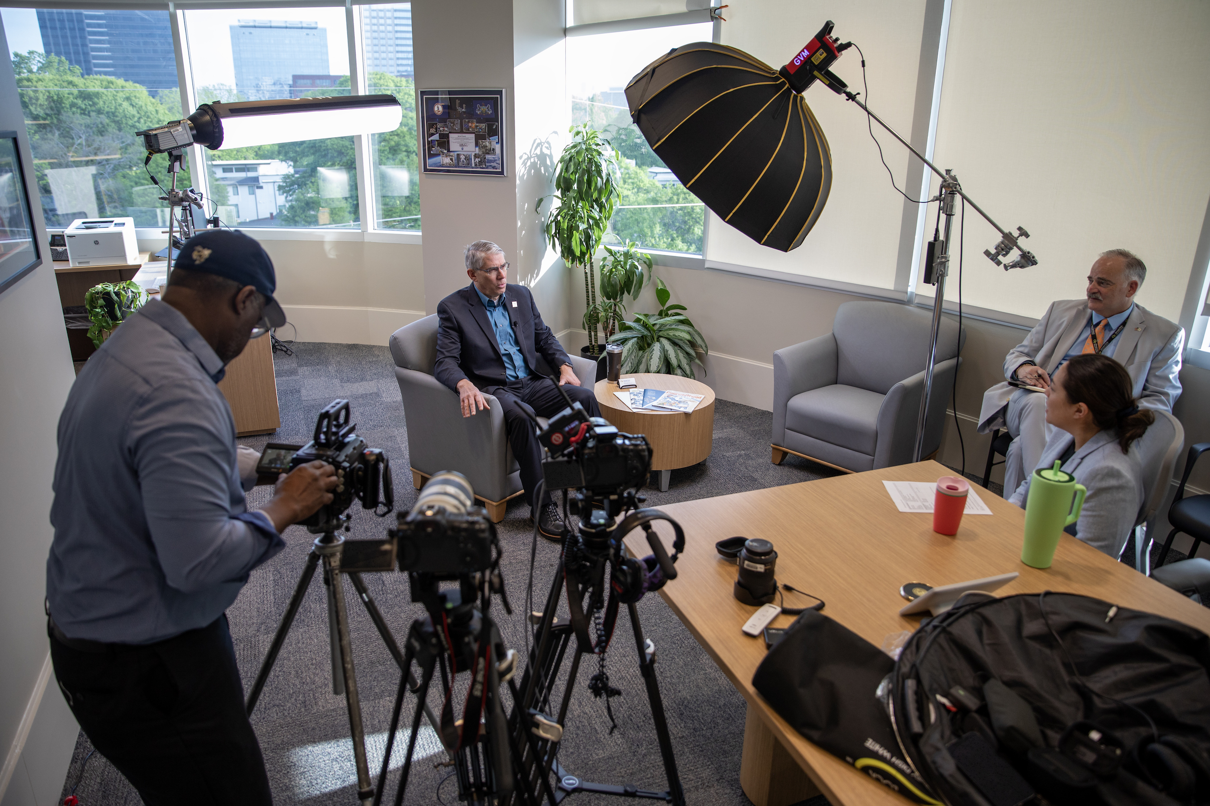 GTRI Director Mike Gazarik sits down for a podcast interview surrounded by lights and camera inside an office
