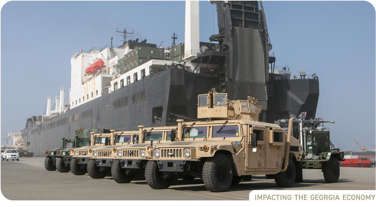 Large ship at dock with row of Humvee vehicles parked in formation in front