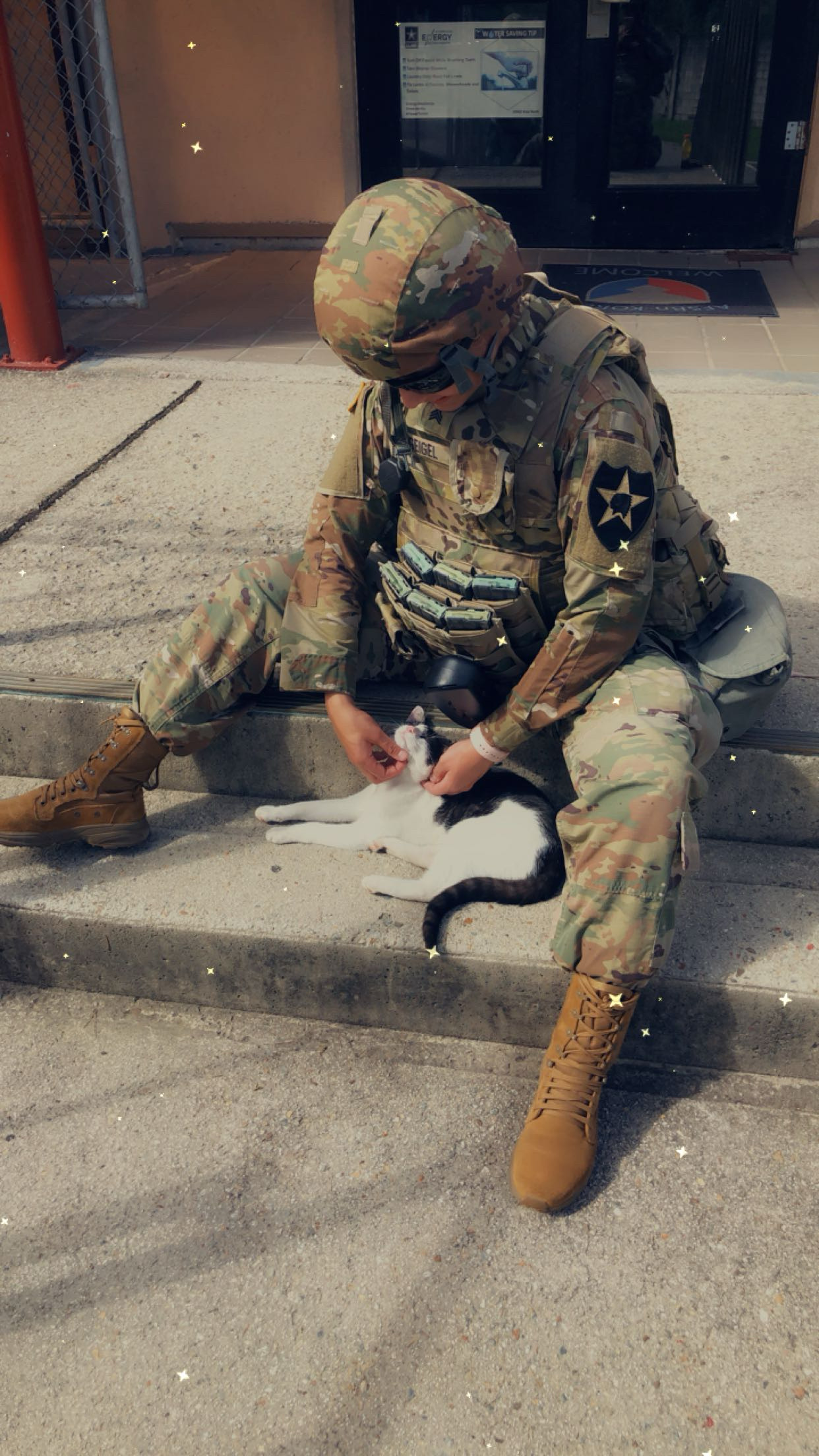 Stephanie Geigel is approached by a random cat as she sits awaiting a field exercise. The cat was made a "mascot" by her fellow soldiers on base at Fort Eisenhower, Georgia.