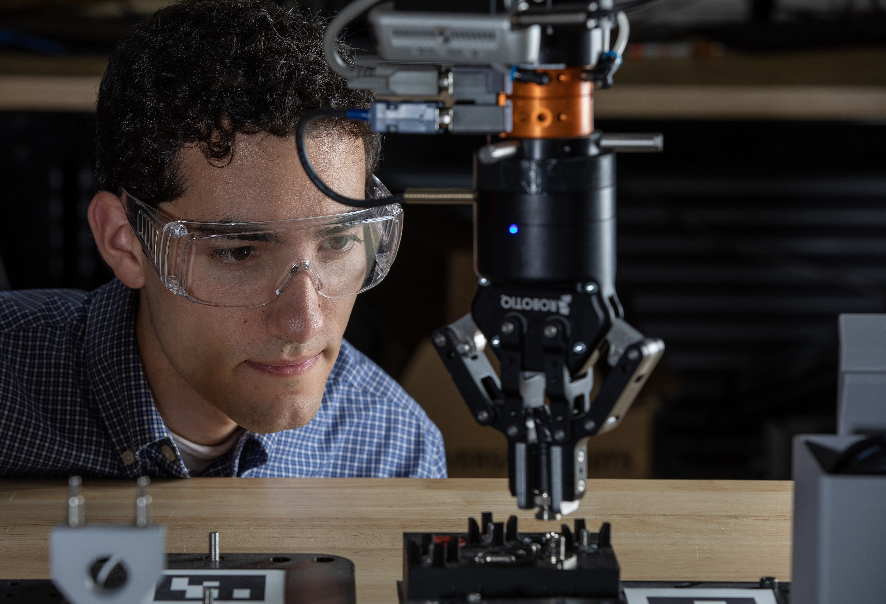 Researcher examines a robotic grasper holding a connector