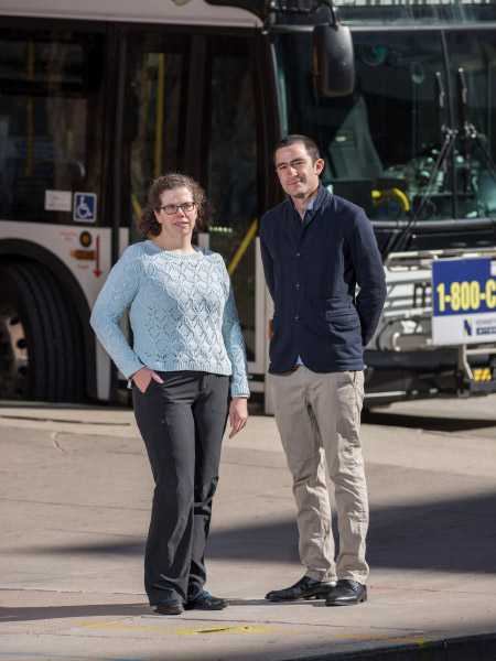 photo of female and male standing in front of city bus