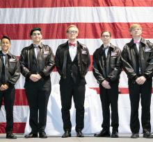 nine people standing in front of American flag accepting an award