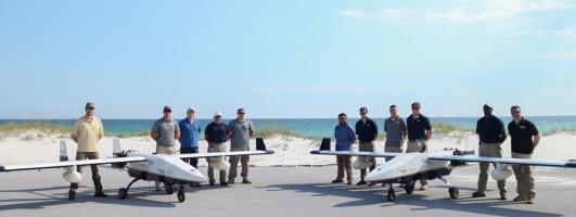 GTRI employees standing behind two UAVs