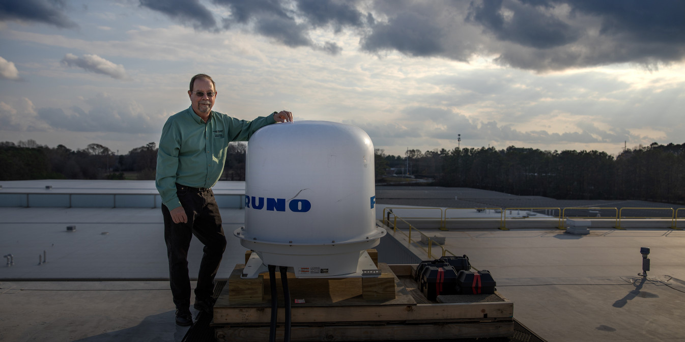 John Trostel standing next to new radar unit on the roof of GTRI's Cobb County facility