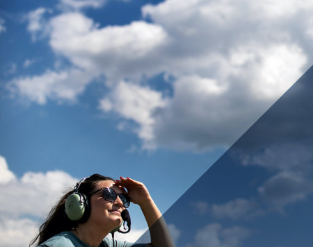 GTRI researcher wearing sunglasses and ear protection looking into blue sky with clouds