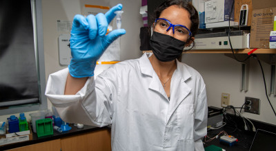 Woman research holds up small vile of clear liquid.