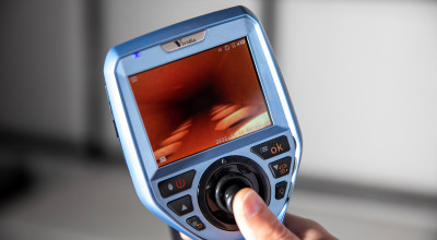 Researcher's hand holds measuring device that contains a display screen and control buttons.