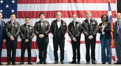 nine people standing in front of American flag accepting an award