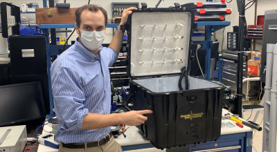 GTRI researcher Robert Harris shows the prototype portable UV disinfection chamber, which was designed to hold at least one face shield along with face masks. (Credit: John Stone)  