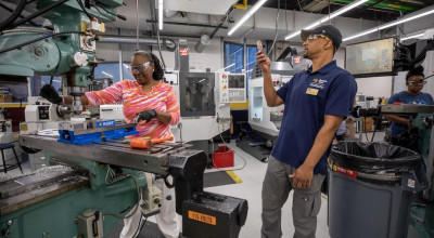 A participant at a Georgia Tech manufacturing workshop cuts metal on industrial equipment.